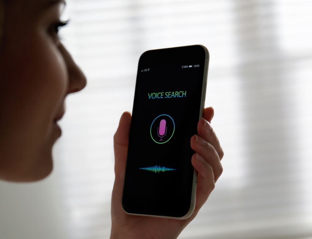 Voice search optimization concept with a person using voice command on a smartphone.